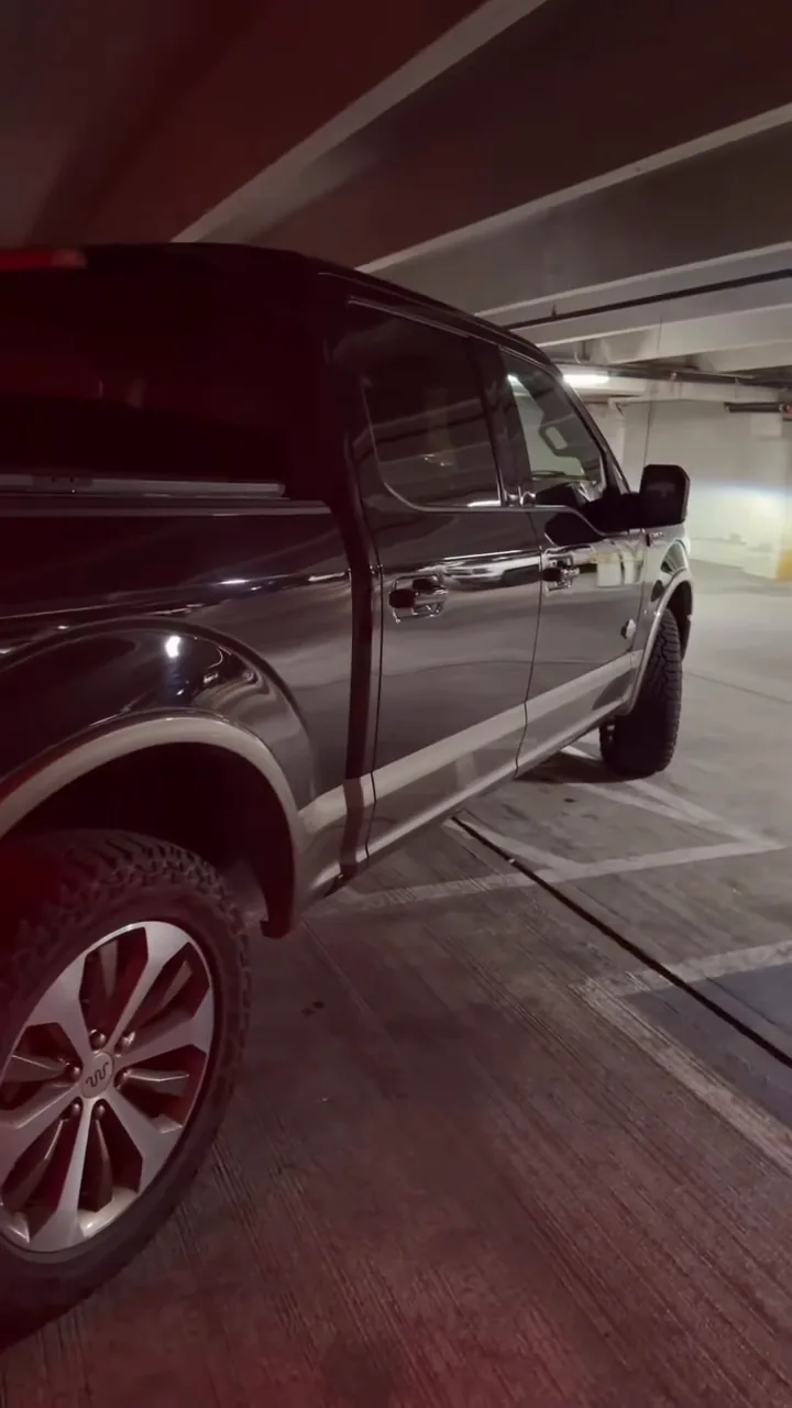 Finished black Ford truck under red garage lighting